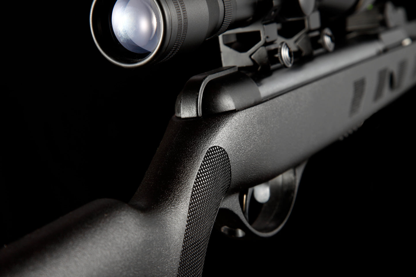 close-up of black air rifle with tactical scope on black background
