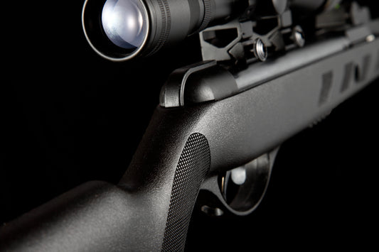 close-up of black air rifle with tactical scope on black background