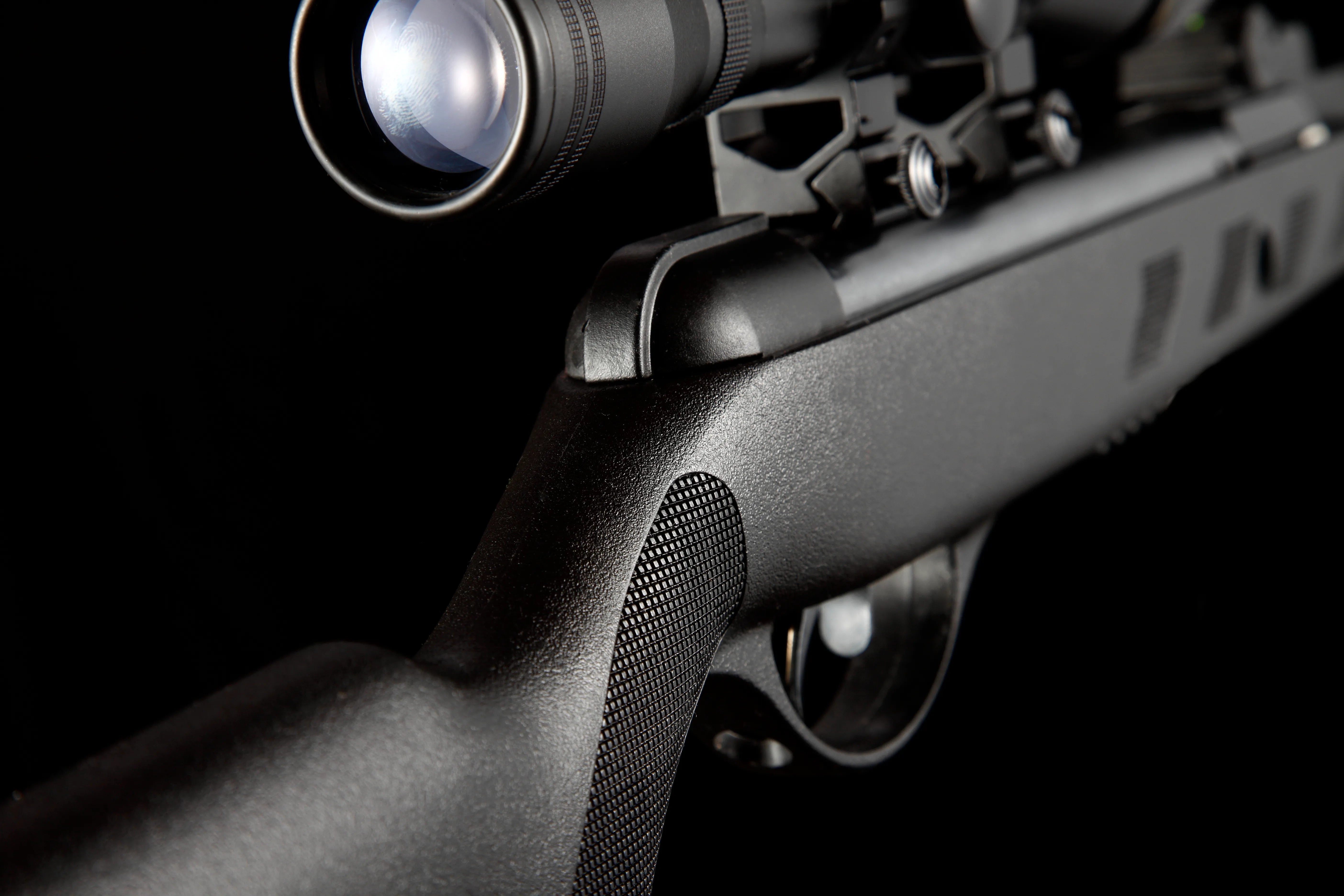 close-up of black air rifle with tactical scope on black background