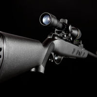 Black air rifle with mounted scope isolated on black background, side close-up view