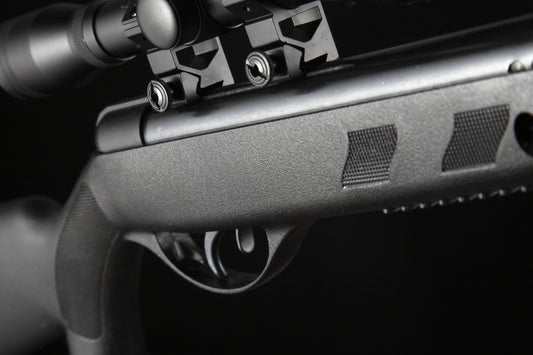 Close-up of a black air rifle trigger and scope mount with textured grip