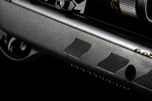 Close-up of textured black air rifle body with trigger and scope adjustment dial